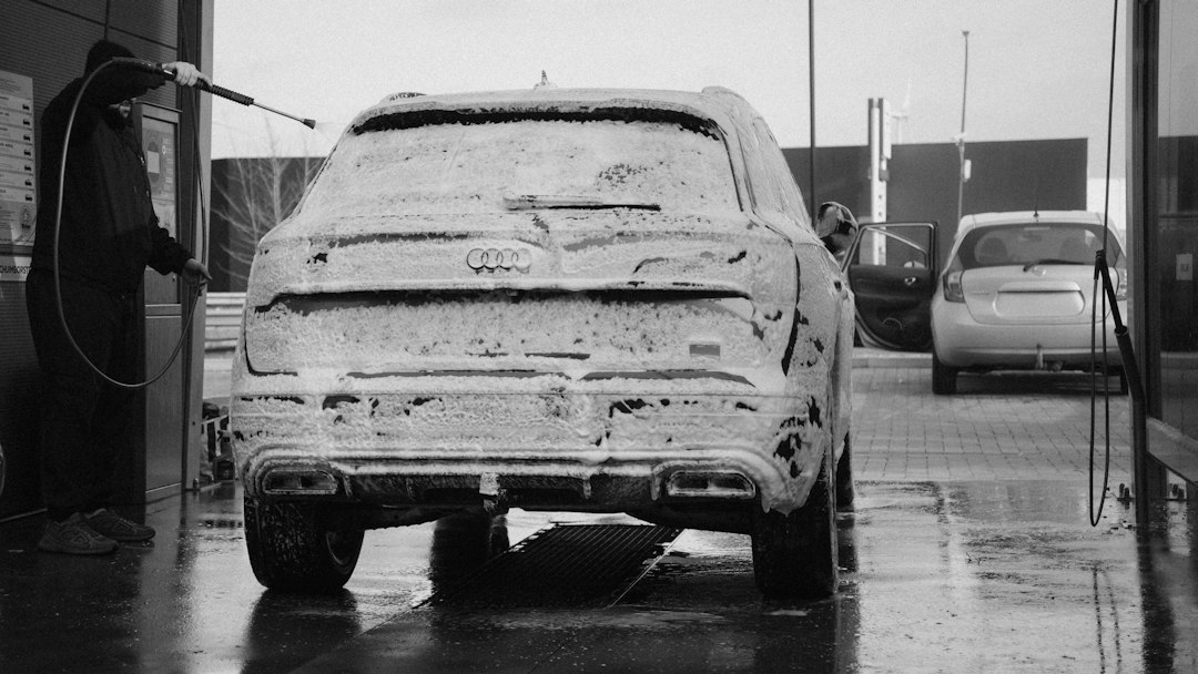 A carwash worker washing a foamy car