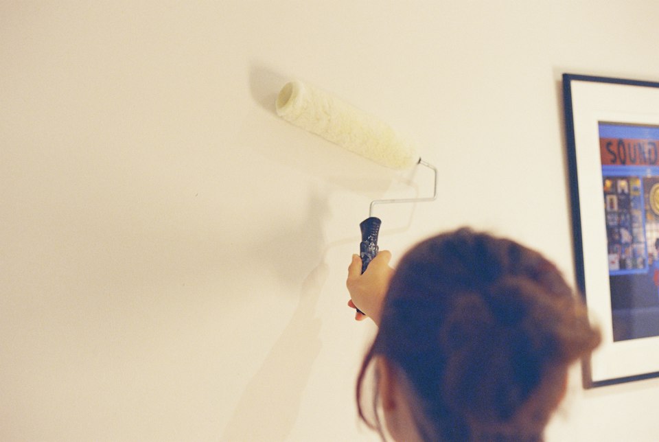 Woman applying paint to a room wall using a roller